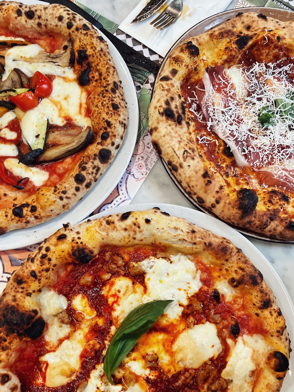 assorted gourmet neapolitan pizzas on marble table